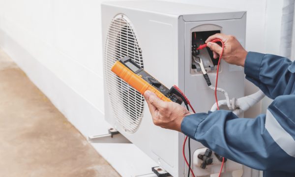 Air conditioner technician repairing central air conditioning system with outdoor tools